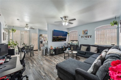 Living area featuring a textured ceiling, wood finished floors, and ceiling fan