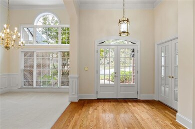 Entrance foyer featuring french doors, a chandelier, crown molding, light wood finished floors, and a towering ceiling