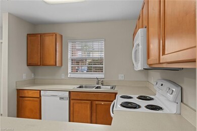 Kitchen with window above sink, white appliances, 