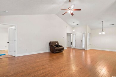 Unfurnished room featuring wood finished floors, ceiling fan, a chandelier, and high vaulted ceiling