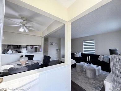 Kitchen with wood finished floors, a textured ceiling, ceiling fan, stainless steel refrigerator, and black microwave