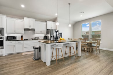 Kitchen featuring decorative backsplash, white cabinetry, a breakfast bar, hanging light fixtures, and dark stone countertops