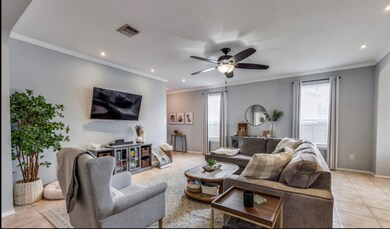 Living room with light tile patterned flooring, ornamental molding, healthy amount of natural light, recessed lighting, and ceiling fan
