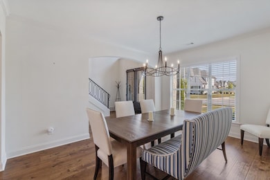 Dining space with dark wood finished floors, crown molding, a chandelier, and stairway
