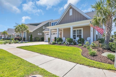 View of front of home with a covered front porch with seating area, custom concrete driveway, a landscaped front yard, and a 2 car garage with tankless hot water heater.