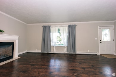 Current - Unfurnished living room with a fireplace, ornamental molding, wood finished floors, and a textured ceiling
