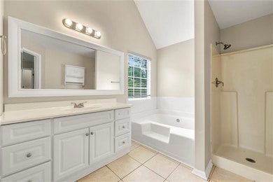 Bathroom featuring tile patterned floors, lofted ceiling, vanity, a bath, and a shower