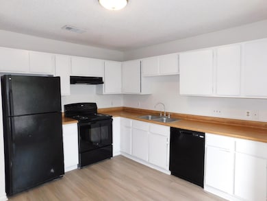 Kitchen with visible vents, white cabinetry, unde