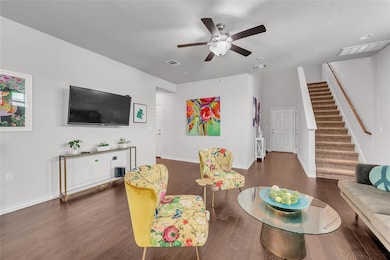 Living area featuring stairs, ceiling fan, wood f