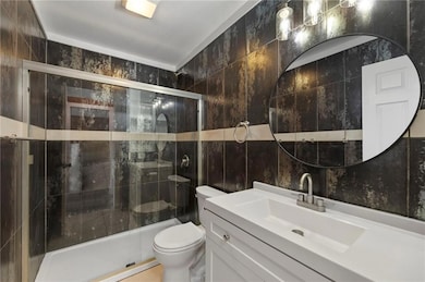 Main floor full bath featuring tile walls, vanity, and a shower stall
