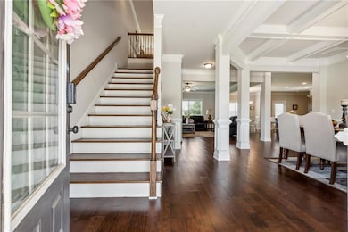 Foyer with ornate columns, ornamental molding, stairs, wood-type flooring, and beamed ceiling