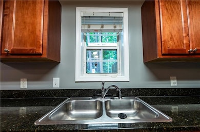 Kitchen with a sink, brown cabinets, and dark stone countertops
