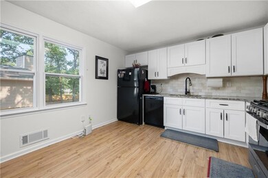 Kitchen featuring black appliances, a sink, light stone countertops, and decorative backsplash