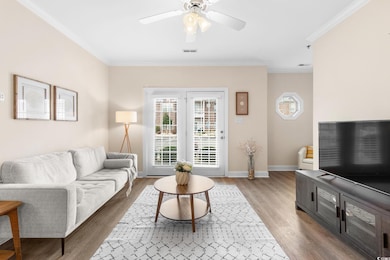 Living area with ornamental molding, light wood-type flooring, and ceiling fan