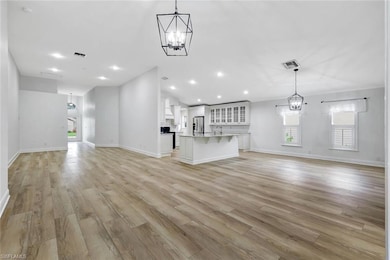 Unfurnished living room featuring a chandelier, light wood-style flooring, vaulted ceiling, and recessed lighting