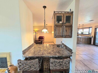 Kitchen with pendant lighting, a textured ceiling, tile patterned floors, open floor plan, and dark stone countertops