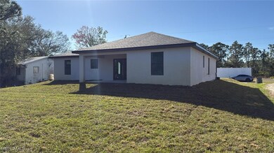 Back of property with a lawn, fence, and stucco si