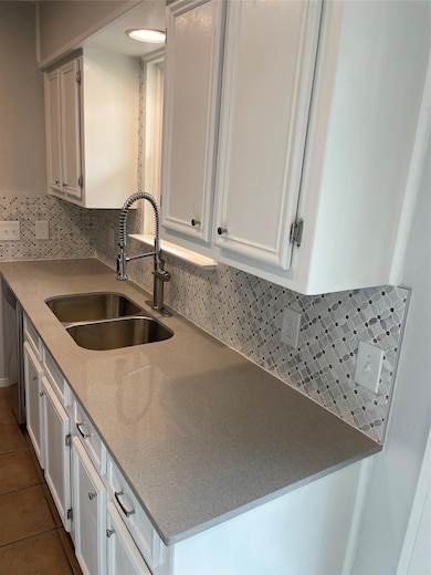 Kitchen with a sink, white cabinets, backsplash, 