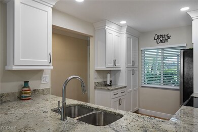 Kitchen featuring white cabinetry, light stone countertops, freestanding refrigerator, and recessed lighting