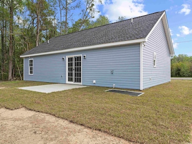 Rear view of property featuring a patio area, a shingled roof, and a lawn