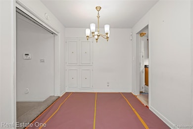 Unfurnished dining area featuring a chandelier and baseboards