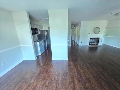 Unfurnished living room featuring dark wood-type flooring, a fireplace with flush hearth, and a textured ceiling
