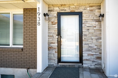Entrance to property with brick siding, covered porch, and stone siding