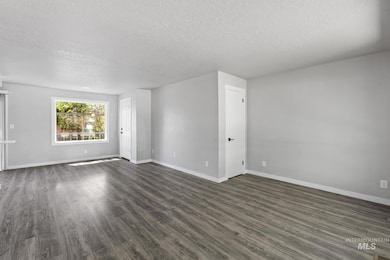 Unfurnished room featuring a textured ceiling and dark wood-style floors