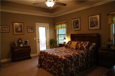 The master bedroom, has a trey ceiling, & a door leading out to the covered porch