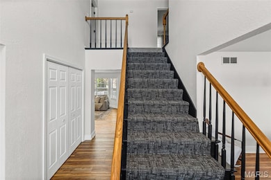 Staircase with wood finished floors, a towering ceiling, and a textured wall