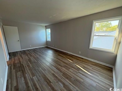 Spare room featuring wood finished floors and base