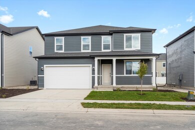 Traditional home with covered porch, concrete driveway, a garage, roof with shingles, and a front lawn