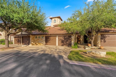 Mediterranean / spanish home featuring a tiled roof, driveway, stone siding, and stucco siding
