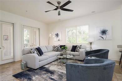 Living area featuring stone tile floors, ceiling fan, and french doors
