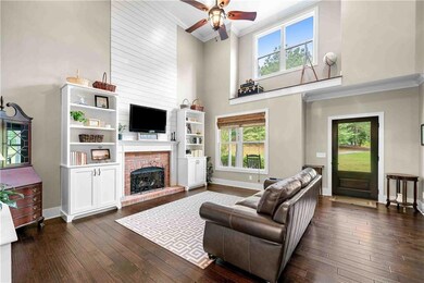 Living room with a high ceiling, ornamental molding, dark wood finished floors, ceiling fan, and plenty of natural light