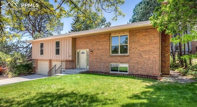 Raised ranch with board and batten siding, an attached garage, brick siding, and driveway