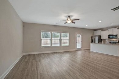 Unfurnished living room featuring ceiling fan and 