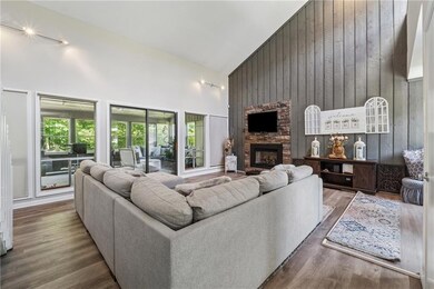 Living room with high vaulted ceiling, a stone fireplace, wood finished floors, and wood walls