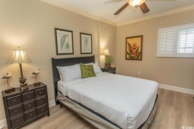 Bedroom with light wood-style flooring, baseboards, crown molding, and a ceiling fan