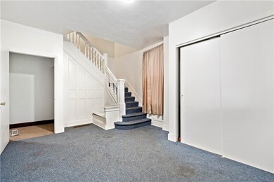 Entryway.  Unit 1 is accessed to the left. Basement access is through the small archway and down to the right. Staircase leads to Unit 2.  Note common storage area on the right.