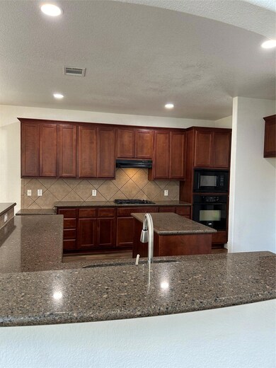 Kitchen with oven, cooktop, range hood, dark ston