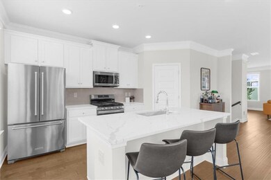 Kitchen featuring appliances with stainless steel finishes, crown molding, backsplash, light wood-type flooring, and light stone countertops