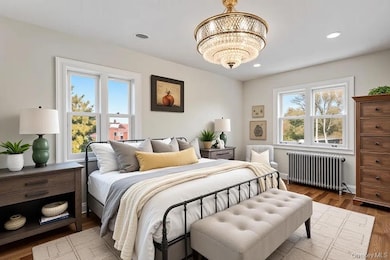 Bedroom with radiator, wood finished floors, recessed lighting, and a chandelier