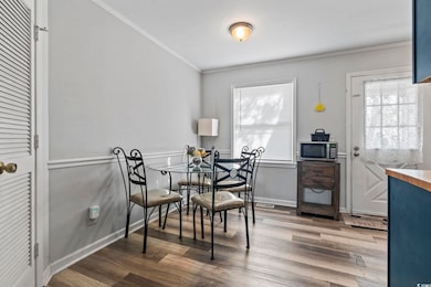 Dining area with wood finished floors and crown molding
