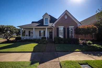View of front of house featuring covered porch, a front lawn, brick siding, and roof with shingles