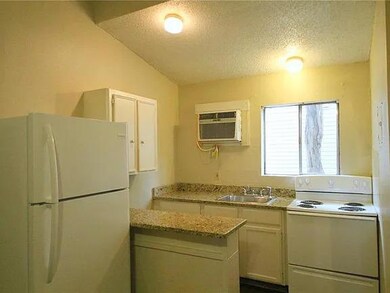 Kitchen with white appliances, a textured ceiling