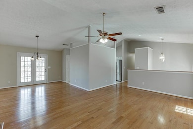 Empty room featuring vaulted ceiling, light wood f