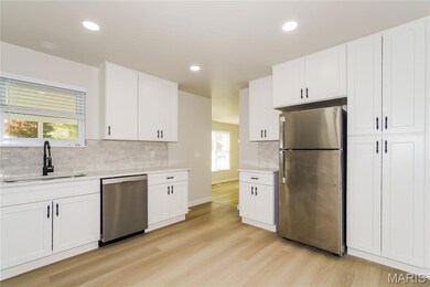 Kitchen with stainless steel appliances, white cabinetry, light wood-style floors, light stone counters, and recessed lighting