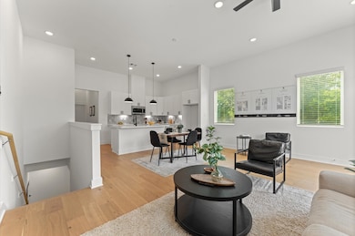 Expansive and light-filled open-concept layout seamlessly combining the living room, dining area, and kitchen on the second floor. The space boasts high ceilings, wide windows for abundant natural light, and elegant flooring that ties the zones together beautifully. The kitchen features modern cabinetry, sleek countertops, and a center island with bar seating—perfect for entertaining or casual meals.