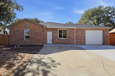 View of front of house featuring a garage, driveway, a shingled roof, and brick siding